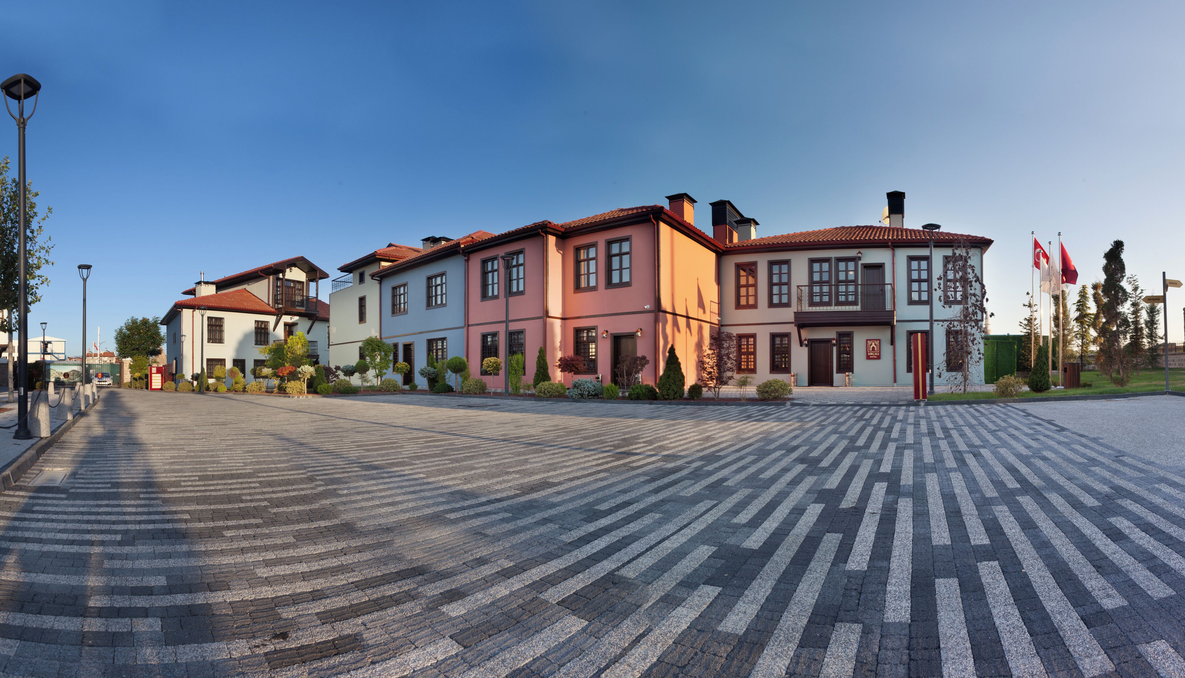 A spacious courtyard with a paved walkway leading to a row of colorful buildings, each with multiple windows and balconies.