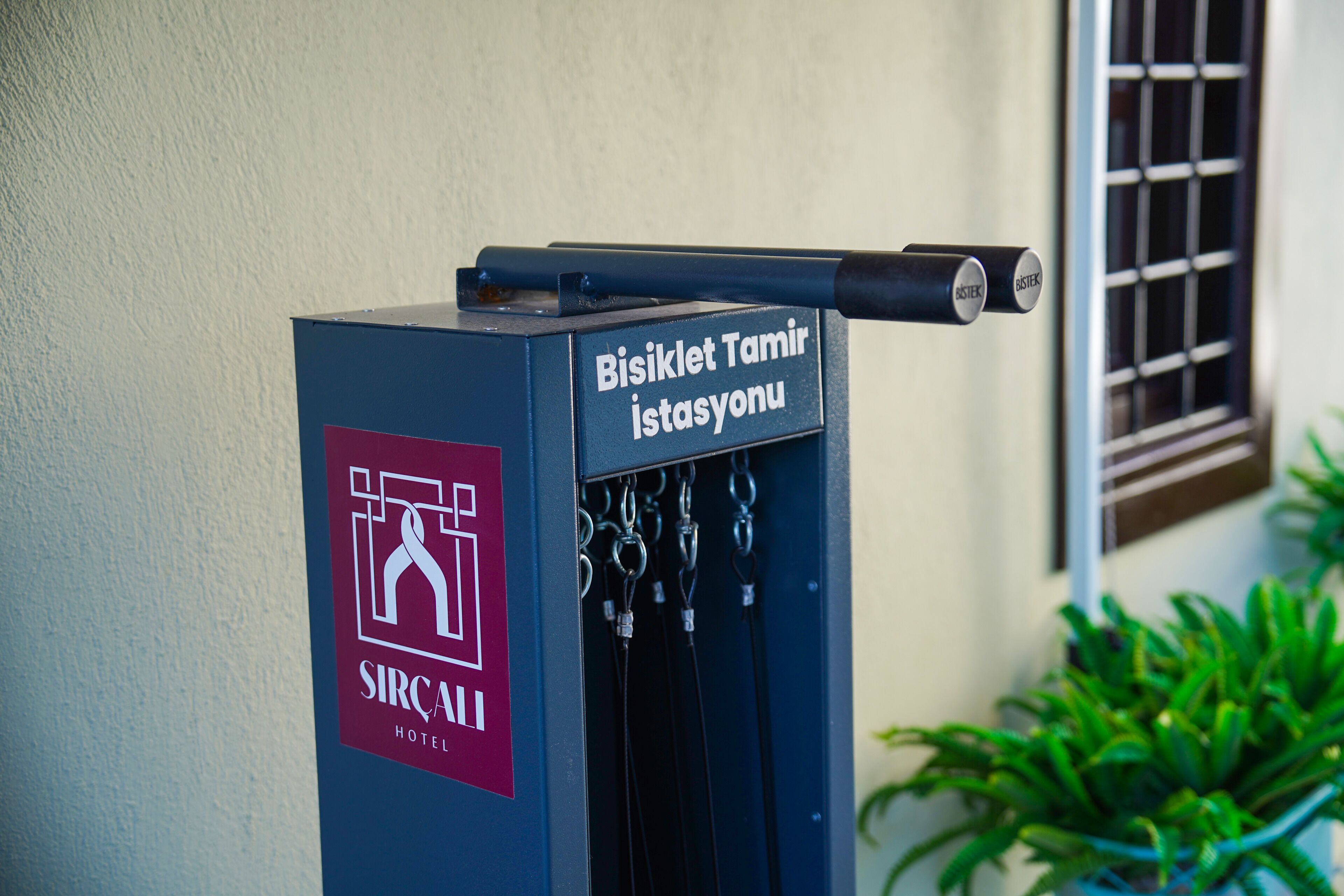 Un kiosque d’information bleu, portant l’inscription « SIRCAI HOTEL » et, au-dessus, une autre inscription indiquant « Station de réparation de vélos ».