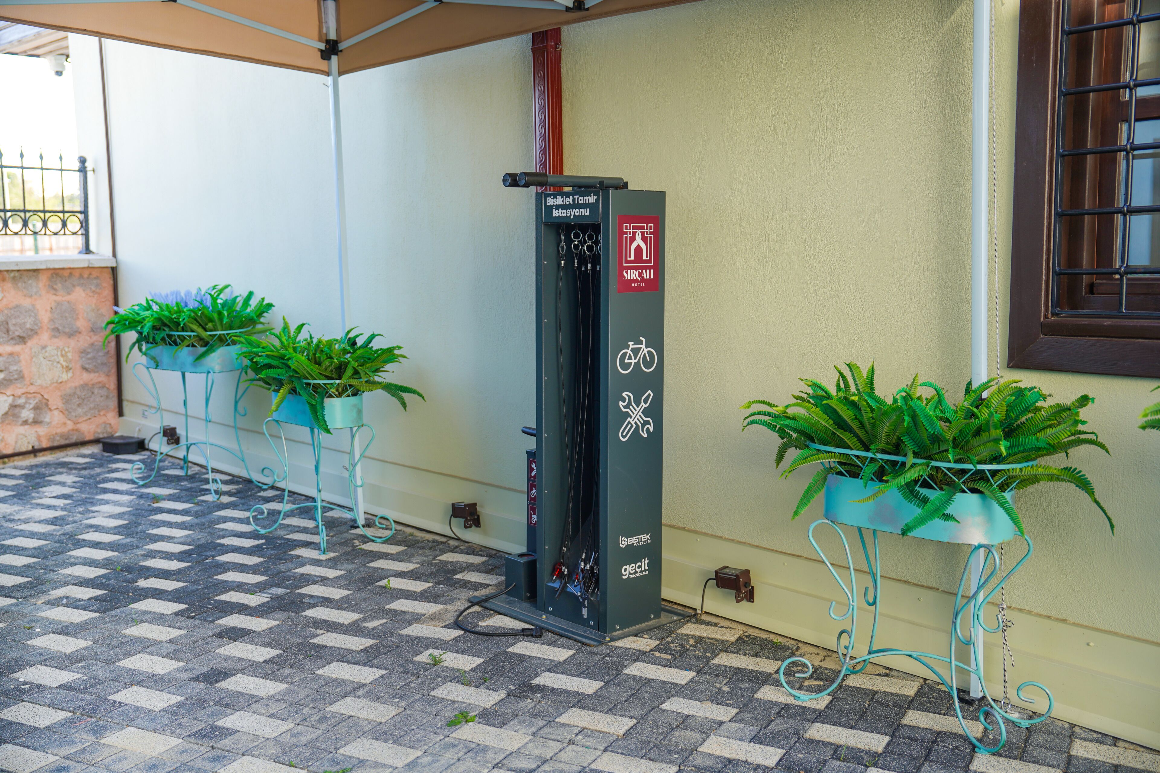 A tiled floor, a utility box, and potted plants.