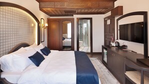 A hotel room with a large bed, a desk with a flat-screen TV, a mirror, and a wardrobe. - SIRÇALI HOTEL (Konya)