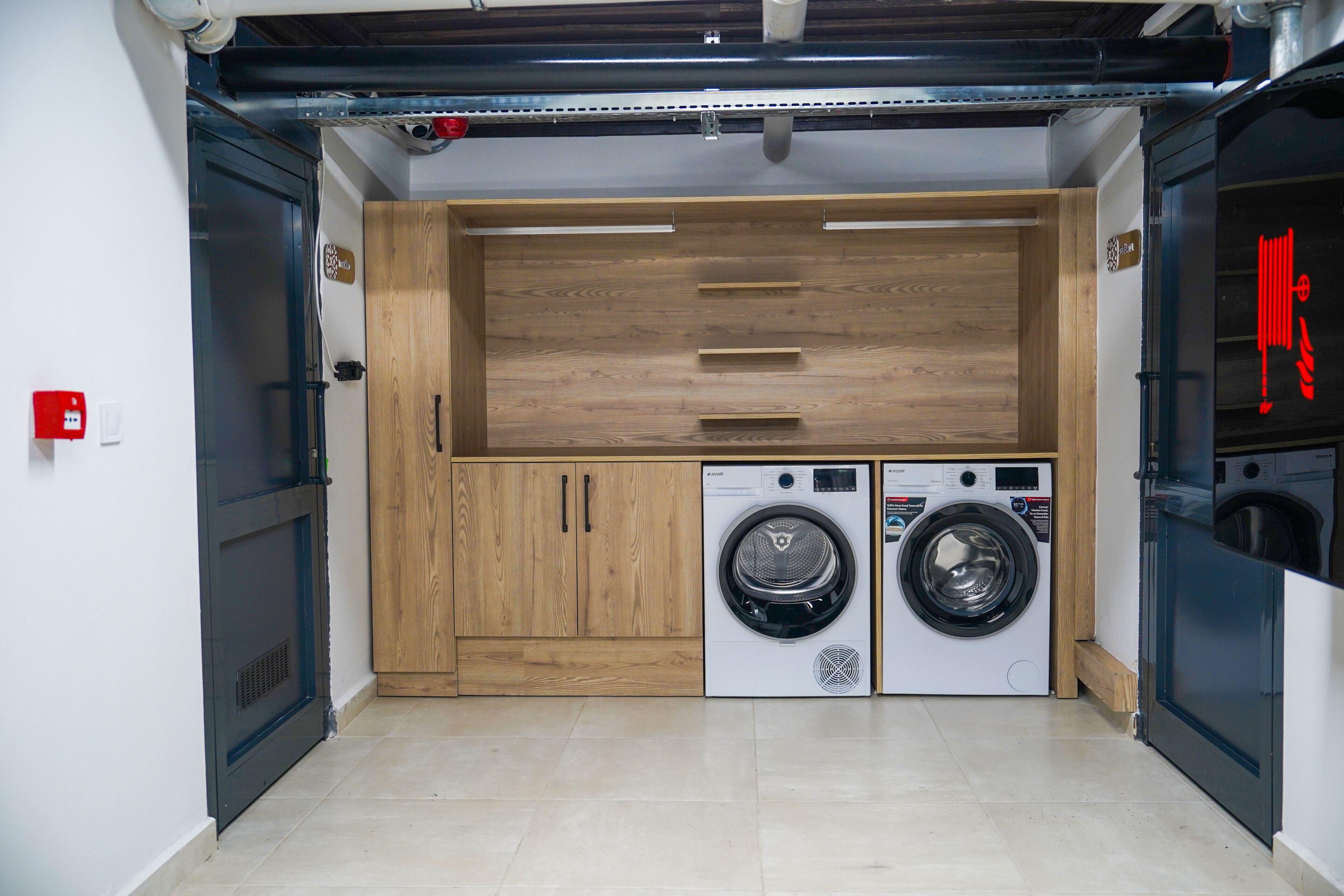 A laundry room with two washing machines, wooden cabinets, and a metal ceiling.