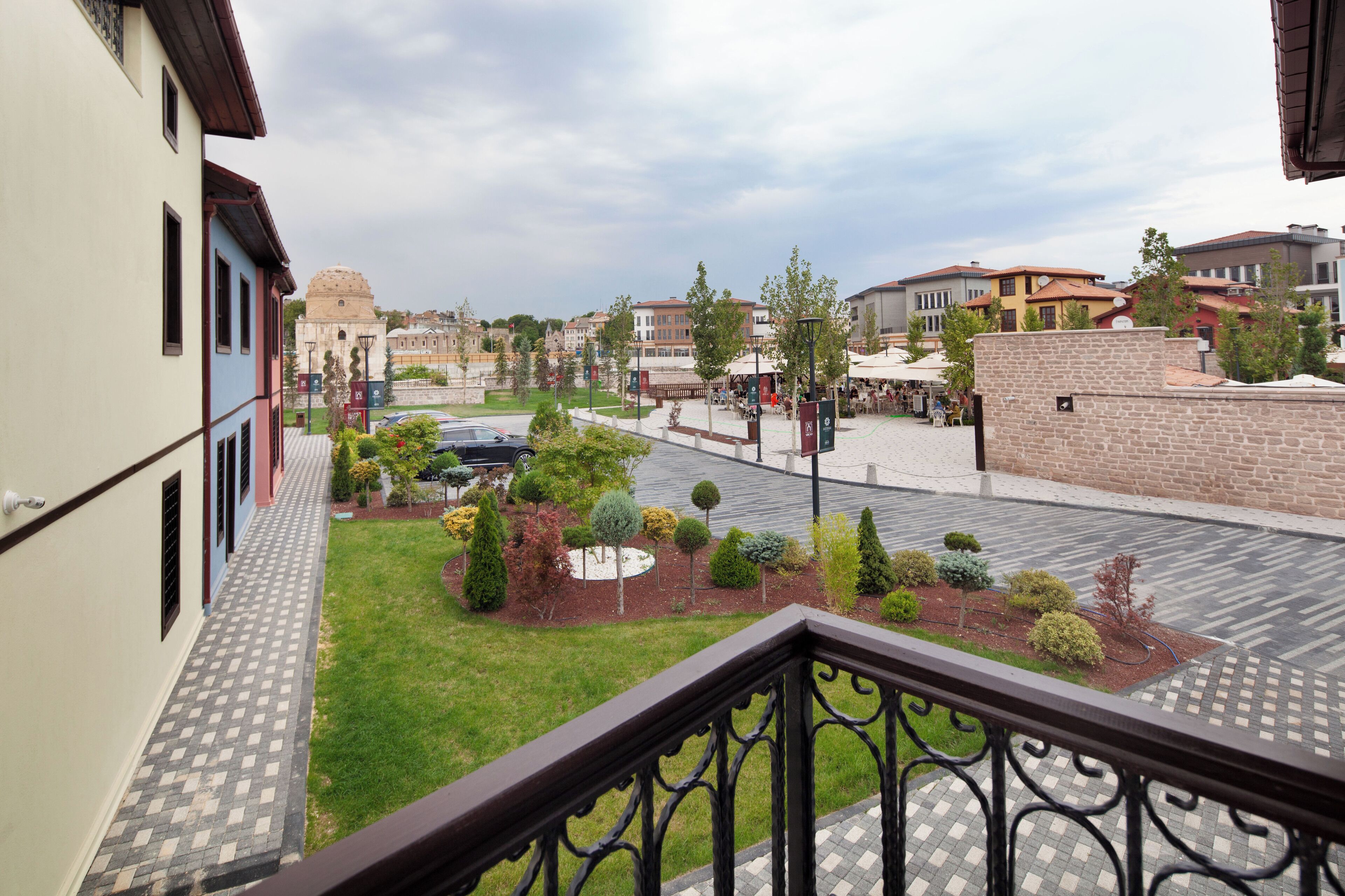 A courtyard with a paved walkway, a small garden with various shrubs, and a view of surrounding buildings.