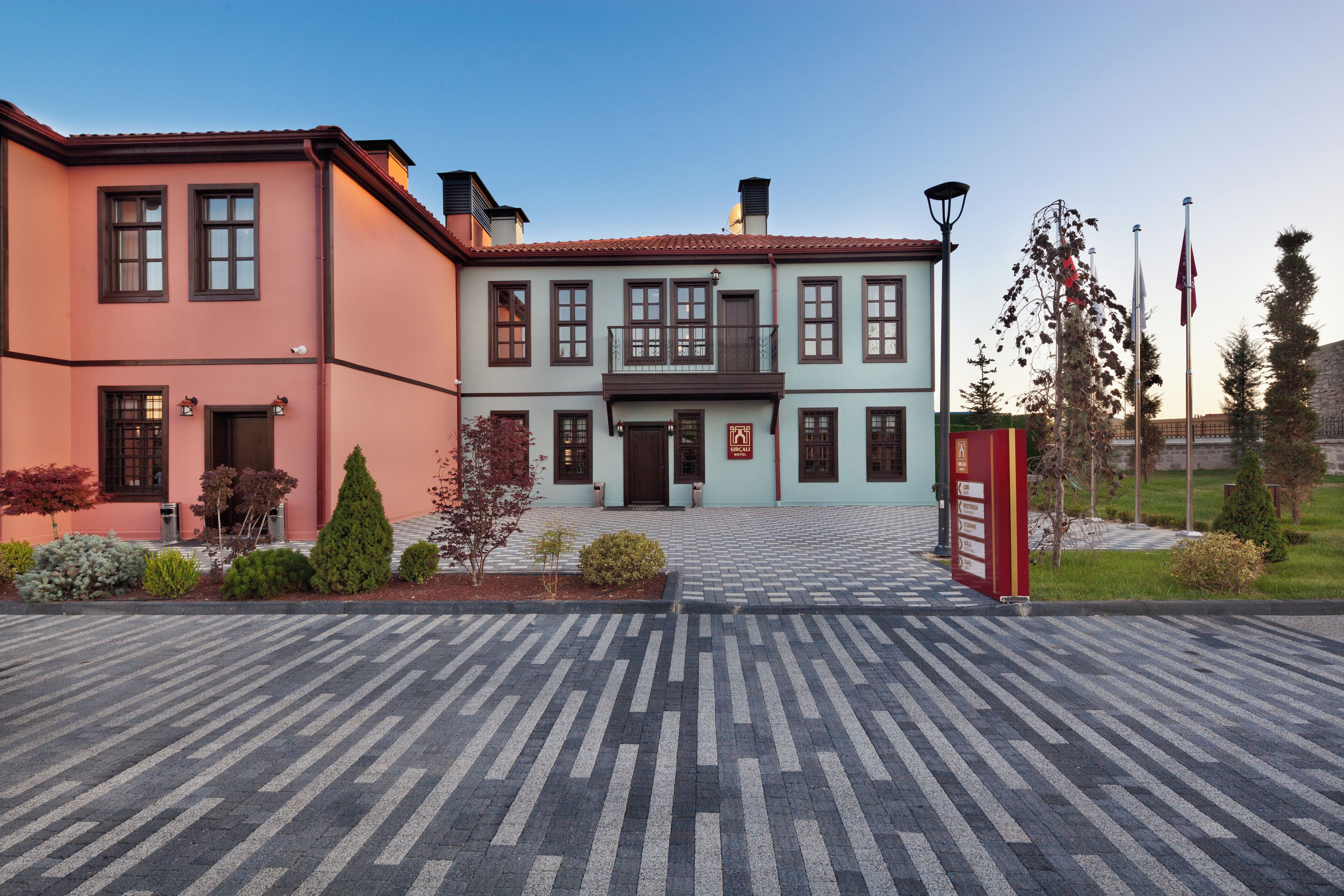 Ein Gebäude mit einem zentralen Eingang, einem gepflasterten Innenhof und einer Fahnenstange.
