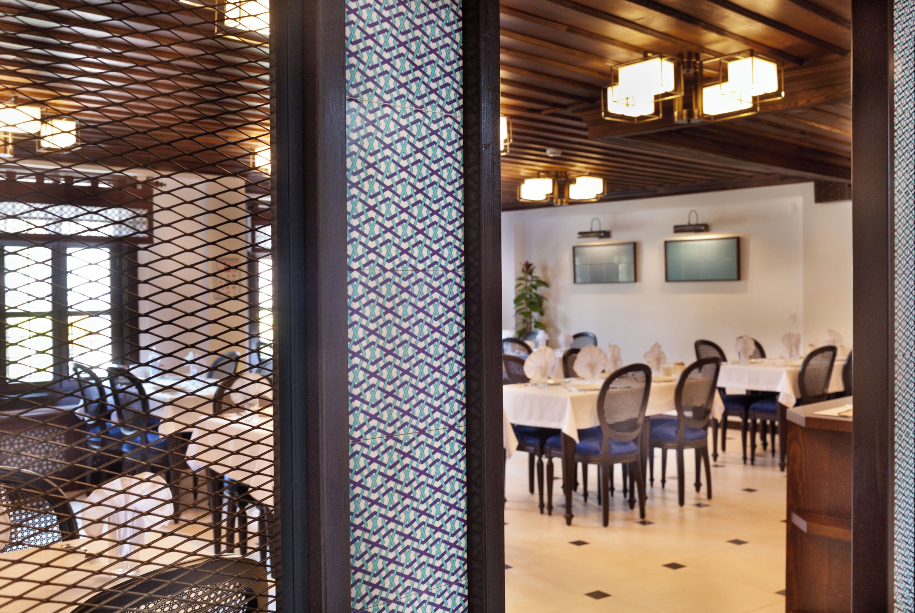 A dining area with tables and chairs, a patterned column, and ceiling lights.