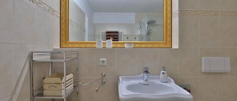 A bathroom with a large mirror, a sink, a toilet, and a shelf with storage boxes.