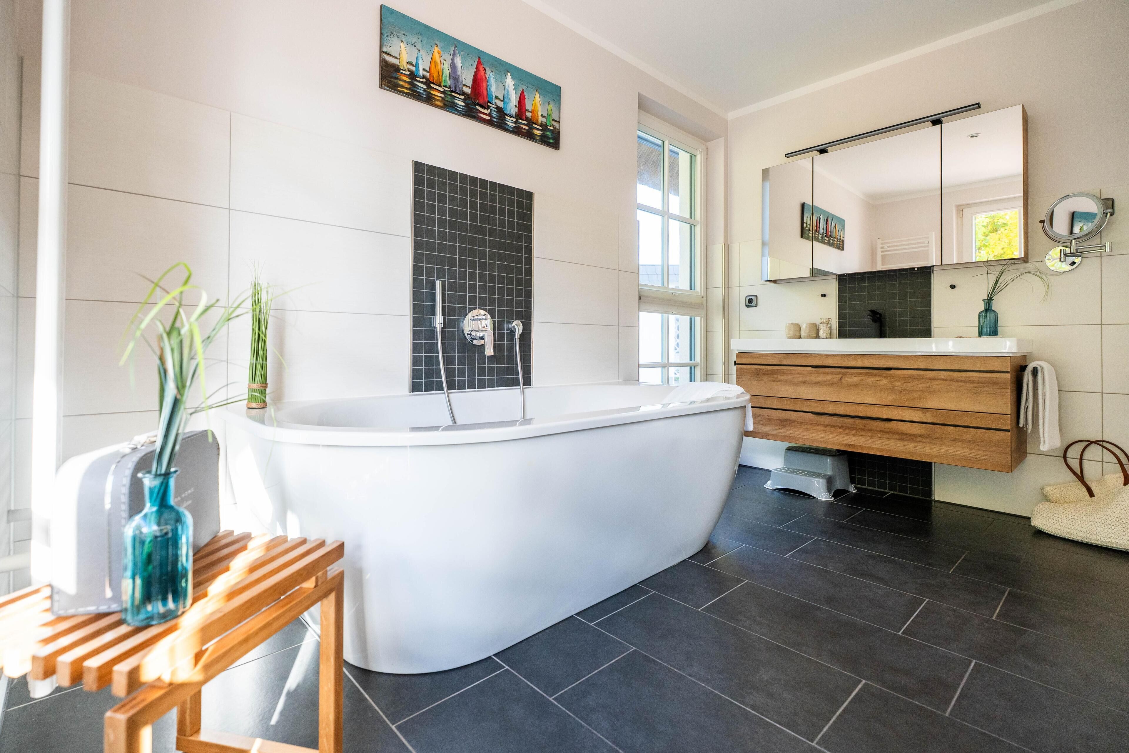A modern bathroom with a freestanding bathtub, a wooden vanity, and a large mirror.