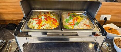 A buffet with two trays of food, one with noodles and vegetables, and another with rice and vegetables.