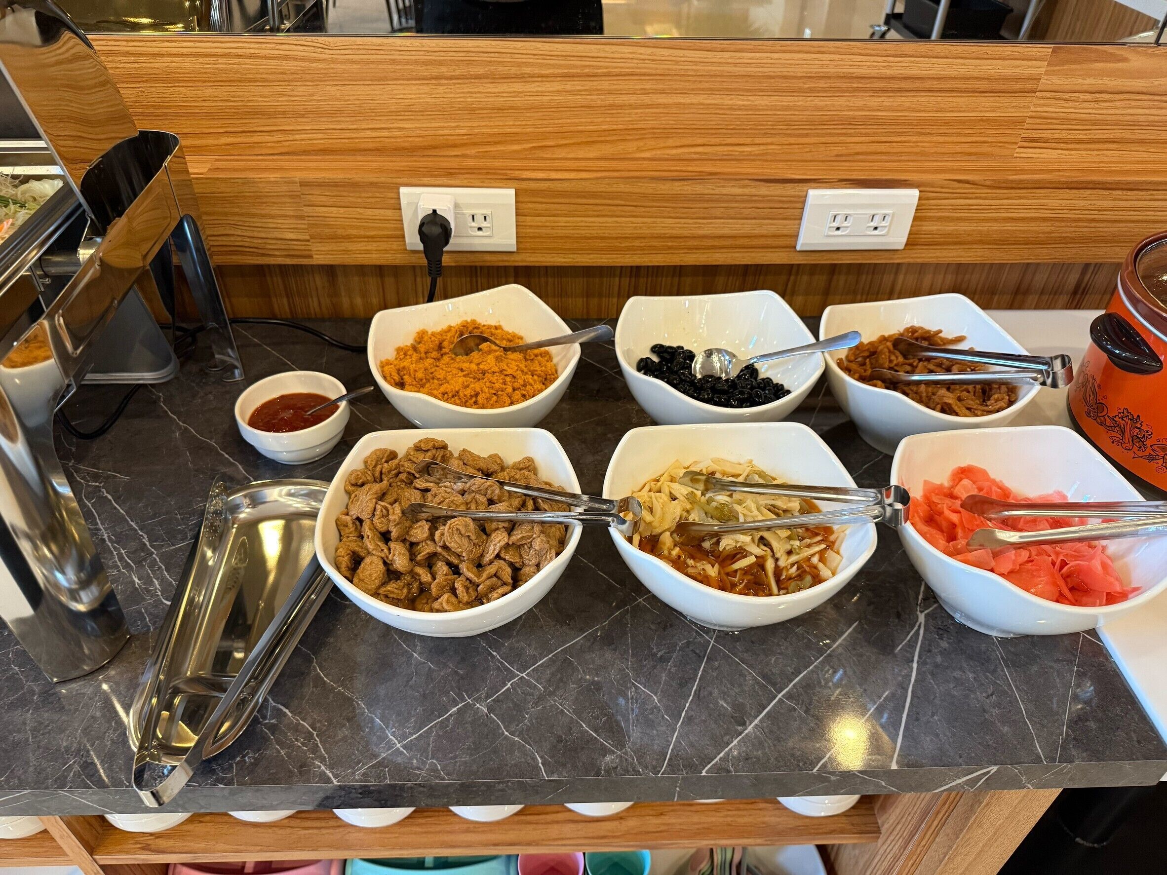 A buffet with various food items in bowls, a coffee machine, and a toaster.