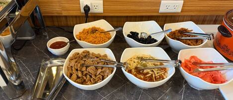 A buffet with various food items in bowls, a coffee machine, and a toaster.