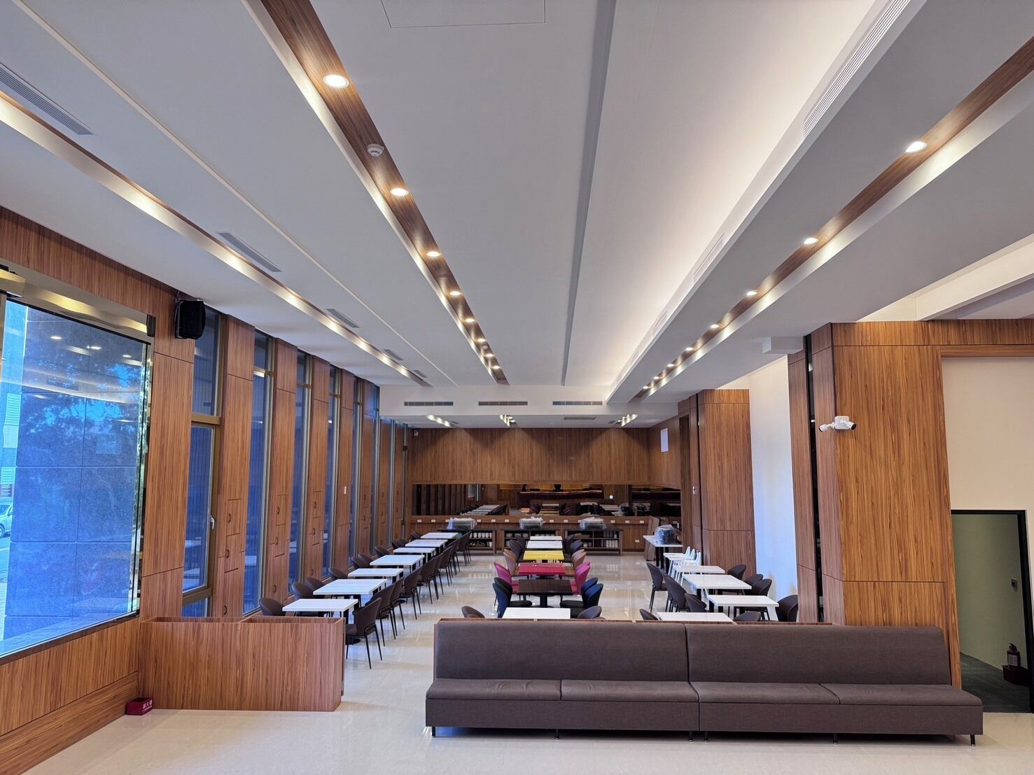 Una sala de conferencias moderna con una mesa larga, un sofá y paneles de madera.