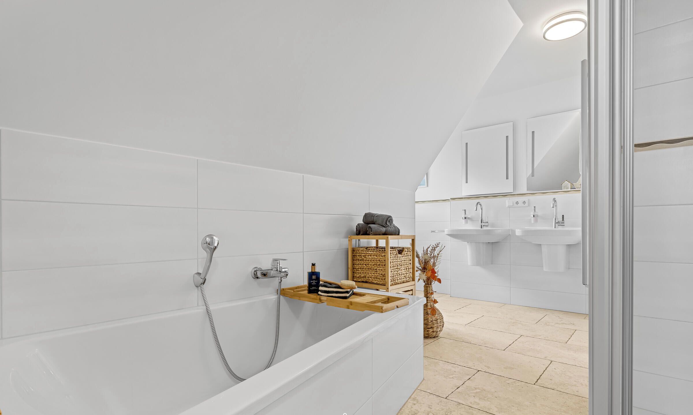 A modern bathroom with a bathtub, a wooden shelf with toiletries, and a shower area.
