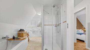 A modern bathroom with a glass shower enclosure, a bathtub, and a vanity with a sink.