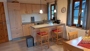 A compact kitchen with wooden cabinets, a small dining table, and two chairs.