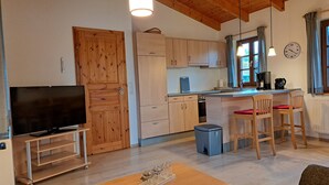 A compact kitchen with wooden cabinets, a built-in oven, and a small island with seating.