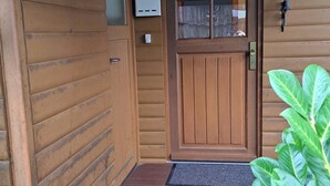 A wooden door with a glass panel, a mailbox, and a bell on the wall.