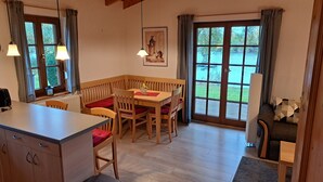 A cozy room with a wooden dining table, chairs, a bench, and a large window with a view of a lake.