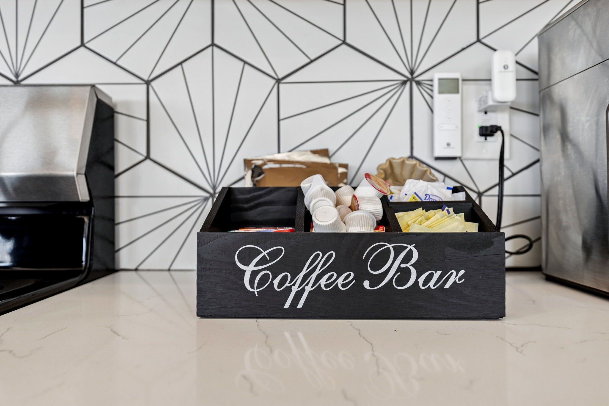 Een keuken met een koffiebar, inclusief een koffiezetapparaat, een doos met de tekst 'Coffee Bar' en diverse koffie-gerelateerde artikelen.
