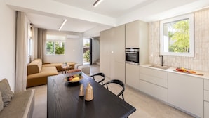 A modern kitchen with a dining area, featuring a wooden table, chairs, and a fruit bowl.