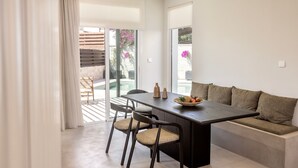 A modern dining area with a dark wooden table, two chairs, and a sofa.