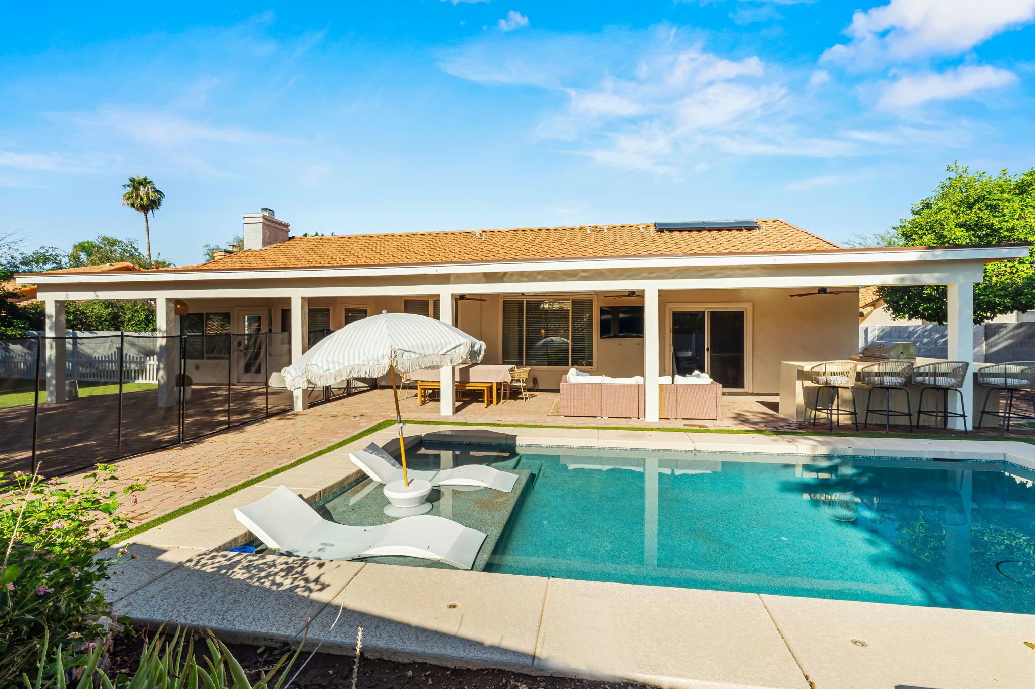 A modern house with a swimming pool, outdoor furniture, and a covered patio area.