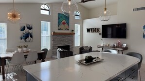A modern kitchen with a large island, pendant lights, a fireplace, and a TV mounted on the wall. - Prime North Scottsdale location with private pool and hot tub (Scottsdale)