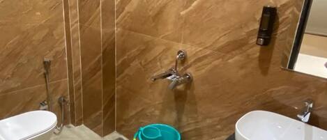 Une salle de bain avec un mur en marbre, une douche, des toilettes et un lavabo.