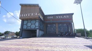 A hotel with a modern design, featuring a prominent 'HOTEL' sign and a restaurant named 'OM VILAS' with a visible entrance and outdoor seating. - Hotel Om Vilas (Mathura)