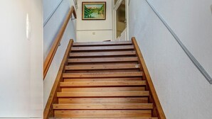 Un escalier en bois avec une rampe, menant à une porte dotée d’un panneau de verre.