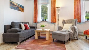 En moderne stue med en grå sofa, et træsofabord og en grå lænestol.