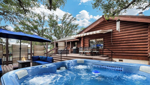 A hot tub with a blue cover, wooden deck, and outdoor seating. - Canyon Lake Haven Cabin Hot Tub Yard BBQ Fire Pit (Canyon Lake)