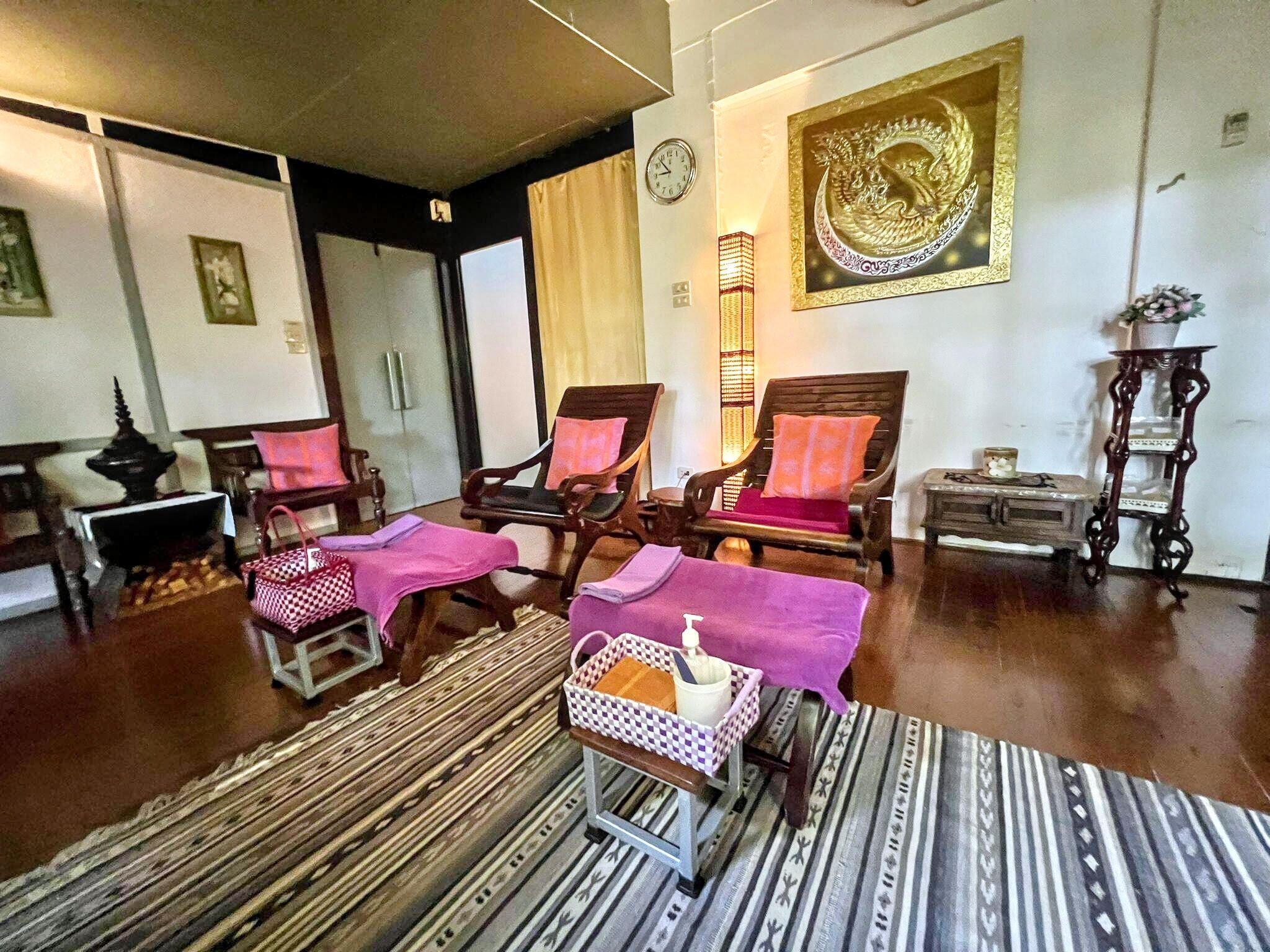 Una habitación con sillas de madera, un tapete estampado, una mesa con una cesta y un adorno en la pared.