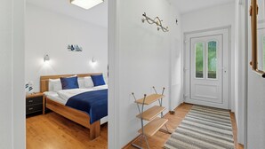 Una camera da letto con un letto di legno, un comodino, una scrivania e una porta che dà su un balcone.