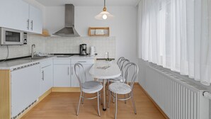 A modern kitchen with white cabinets, a microwave, a stove, and a dining table with four chairs.