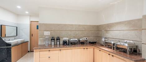 A modern kitchen with a granite countertop, wooden cabinets, and built-in appliances including a coffee maker, toaster, and microwave.