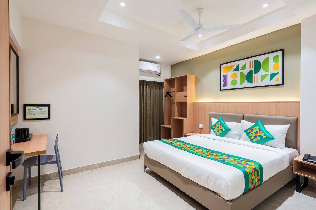 A hotel room with a bed, a desk, a chair, a wardrobe, and a ceiling fan.