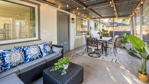 Eine Terrasse im Freien mit überdachter Sitzgelegenheit, einem Tisch und Stühlen sowie Topfpflanzen.