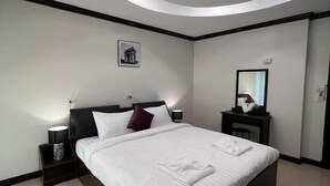 Una habitación de hotel moderna con una cama grande, una mesita de noche, un espejo montado en la pared y una lámpara en el techo.
