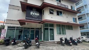 Un edificio de varios pisos con un cartel que dice 'SVAH Boutique Patong' en la planta baja. Varias motocicletas estacionadas adelante.