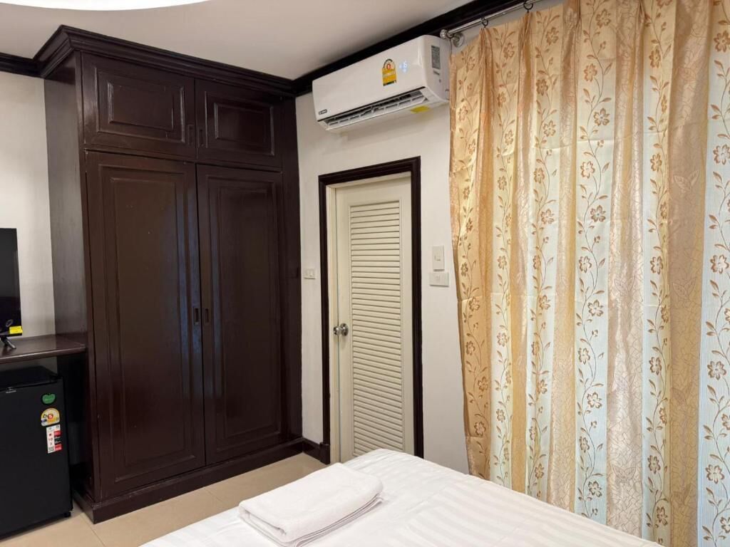 Un dormitorio con cama, armario, puerta y unidad de aire acondicionado.
