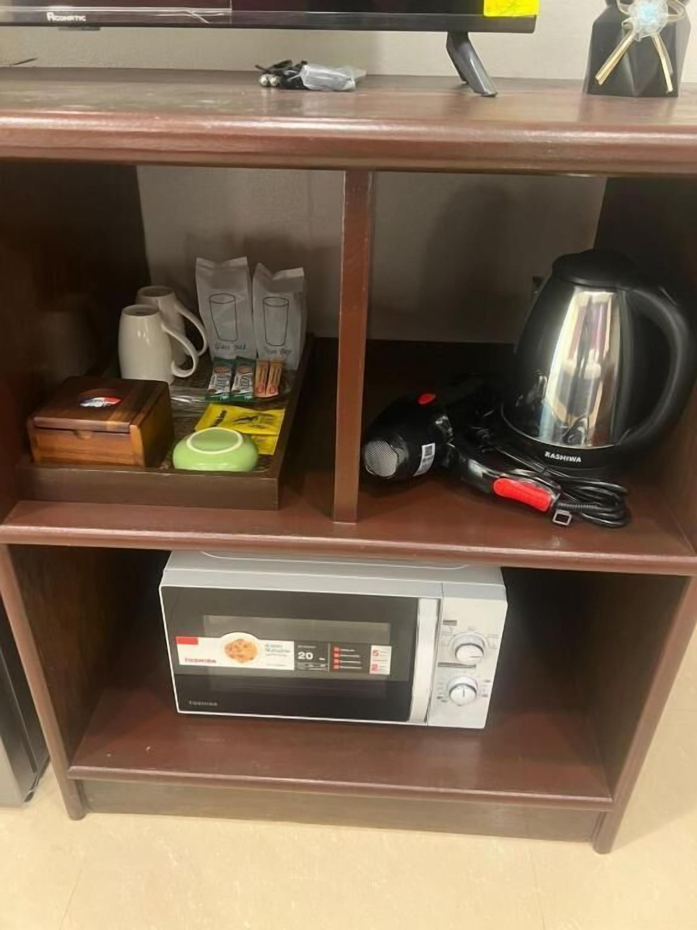 A wooden shelf with a microwave, a coffee maker, and various kitchen items.