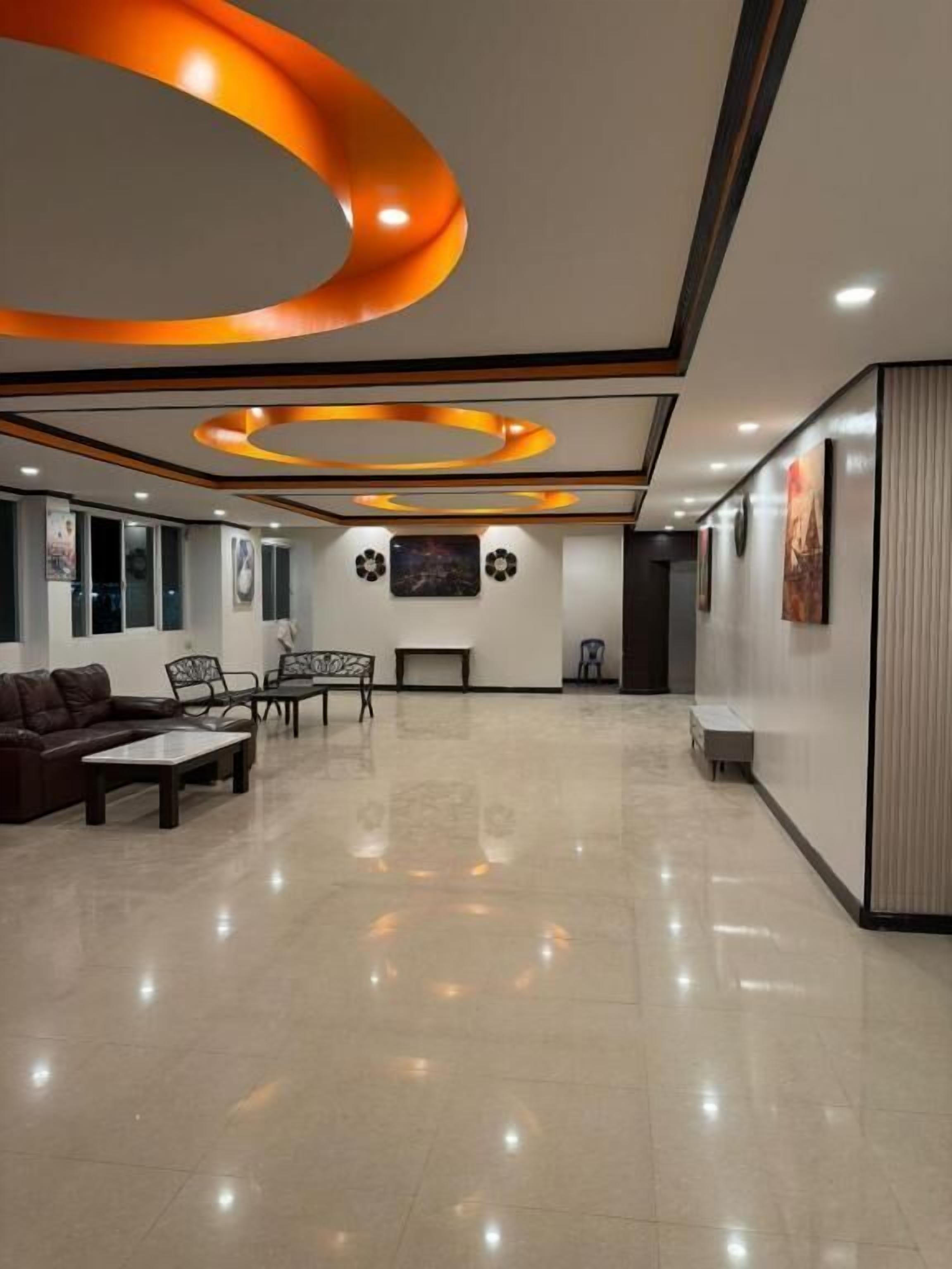 Eine großzügige Lobby mit modernem Design, ausgestattet mit einer Sitzecke mit Sofas und Sesseln, einem Couchtisch und einer Wand mit Kunstwerken.