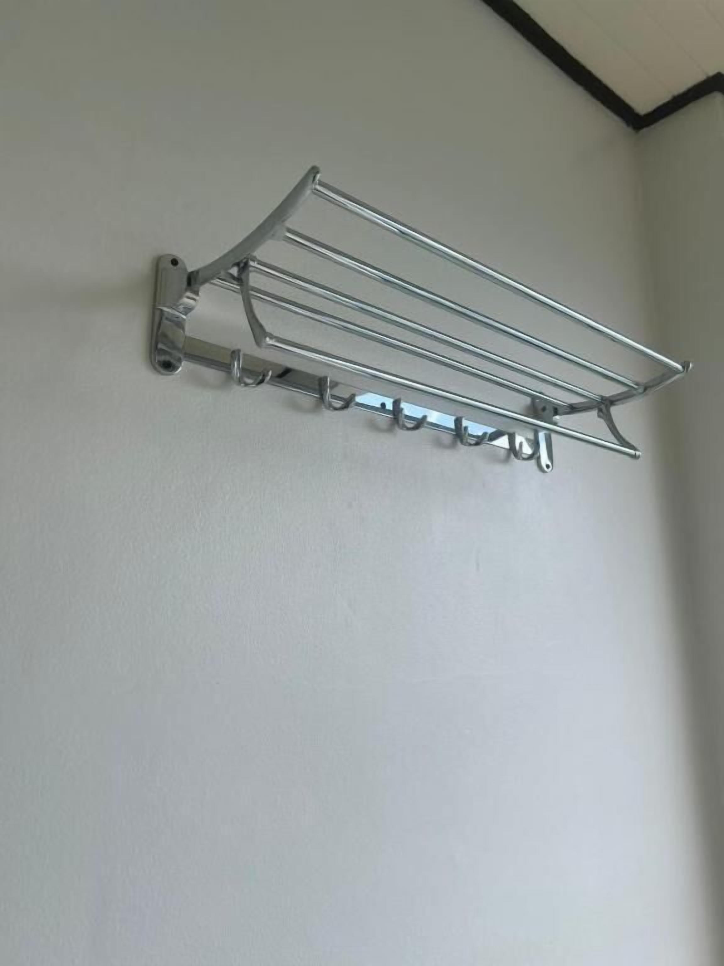 Un étendoir métallique fixé à un mur blanc, avec une bordure noire en haut.