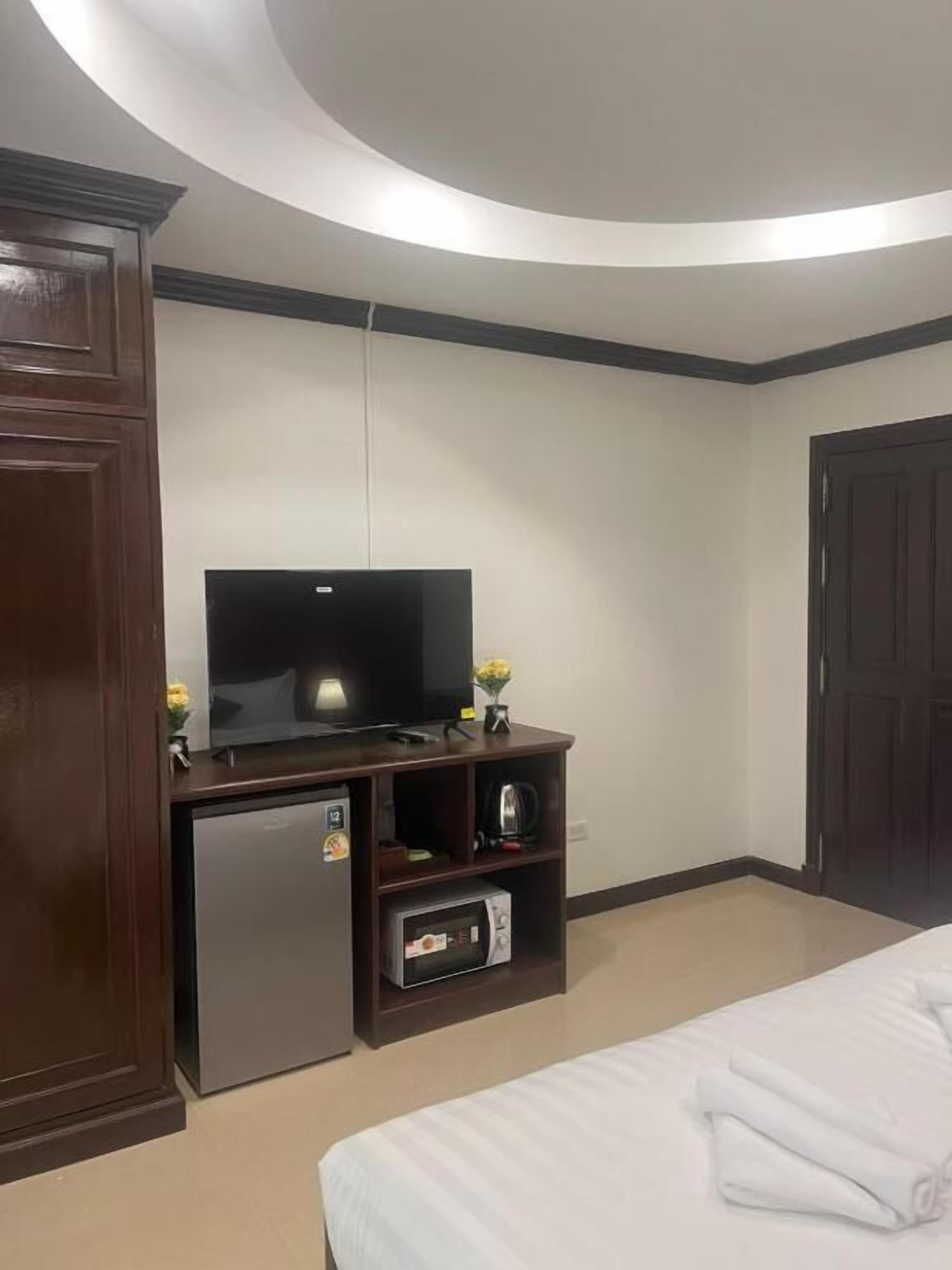 A hotel room with a bed, a TV, a minibar, and a wardrobe.