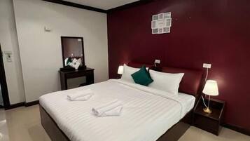 A modern hotel room with a large bed, a nightstand with a lamp, and a wall-mounted artwork.