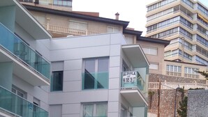Un bâtiment moderne doté d’un espace piscine, comprenant une piscine à l’eau cristalline, des balcons en verre et un panneau indiquant un numéro de téléphone.