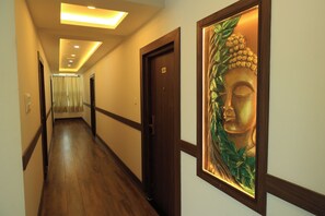 A hallway with wooden flooring, a door with a number plate, and a framed artwork on the wall. - Hotel Vishaka Paark (Coimbatore)