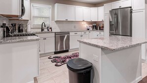 A modern kitchen with white cabinets, stainless steel appliances, and a granite countertop. - Spacious Home In OP|Sleeps 12|5BR|Parking (Overland Park)
