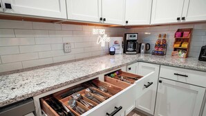 A kitchen with white cabinets, a granite countertop, a coffee maker, and a drawer organizer. - Spacious Home In OP|Sleeps 12|5BR|Parking (Overland Park)