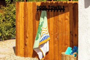 Una cerca de madera con un letrero que dice 'POOL TOWELS' y una cesta con toallas.