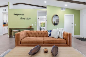 Ein Wohnzimmer mit einem braunen Sofa, einem Couchtisch und einer Wand mit einem motivierenden Zitat.